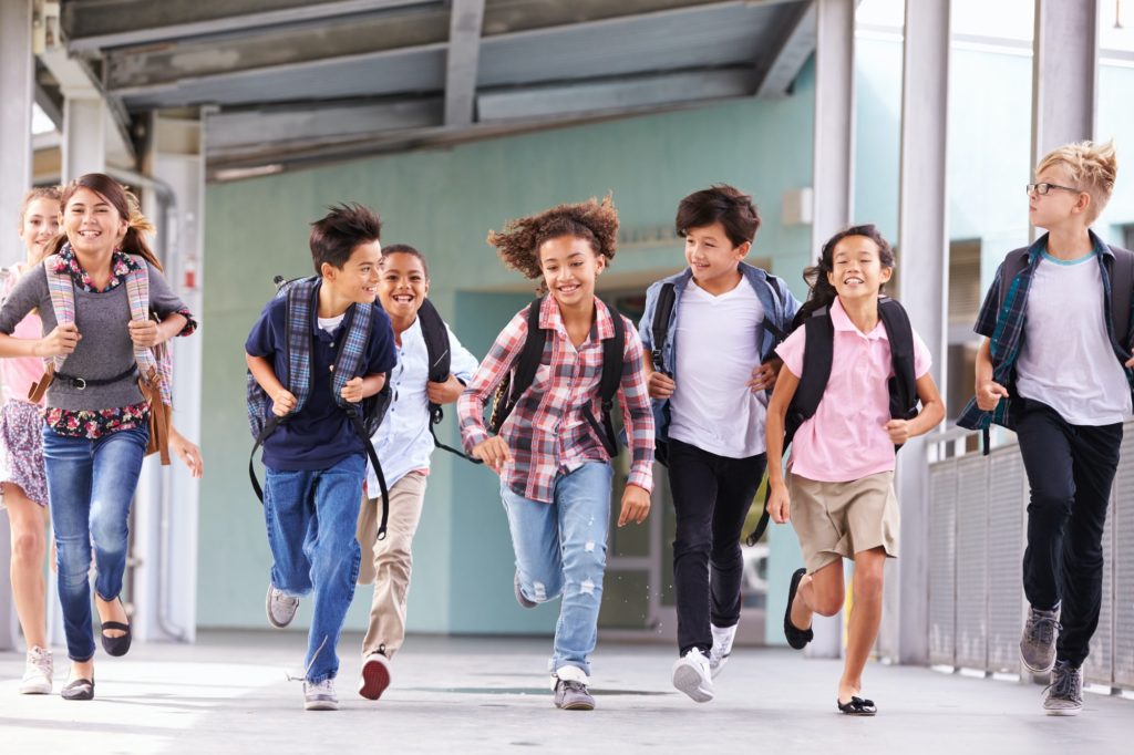 Group of elementary school kids running in a school corridor