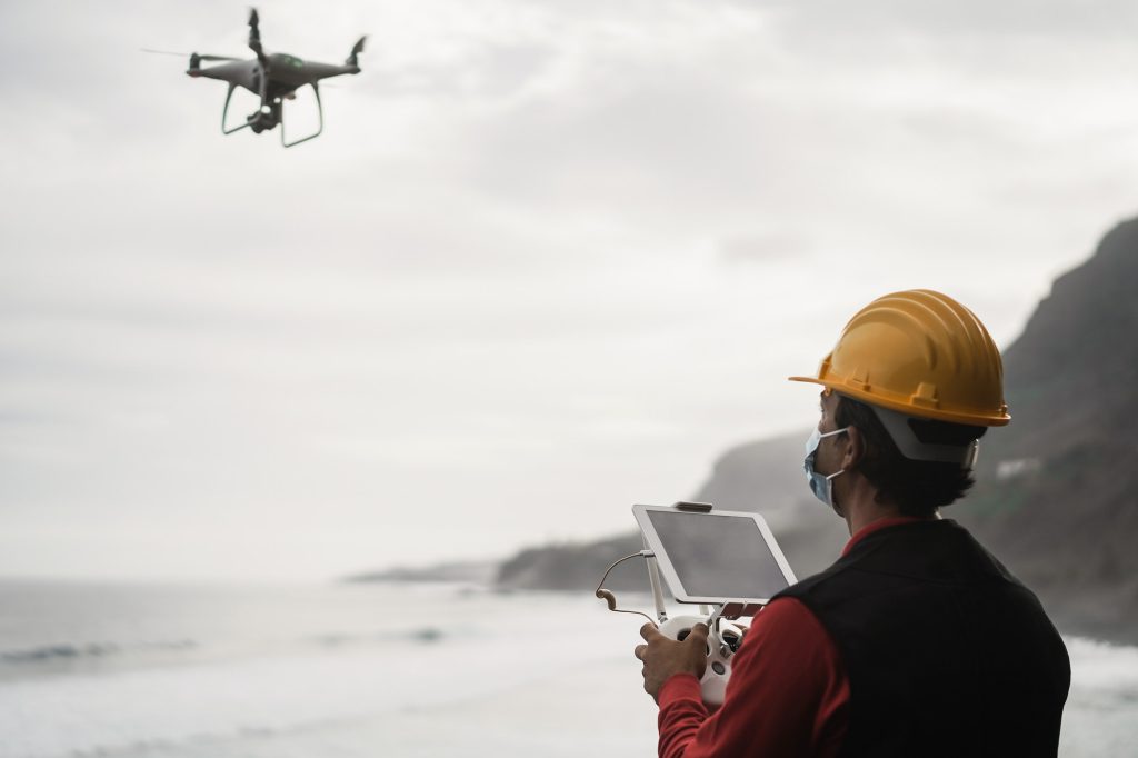 Man engineer flying drone while wearing protective mask - Focus on tablet