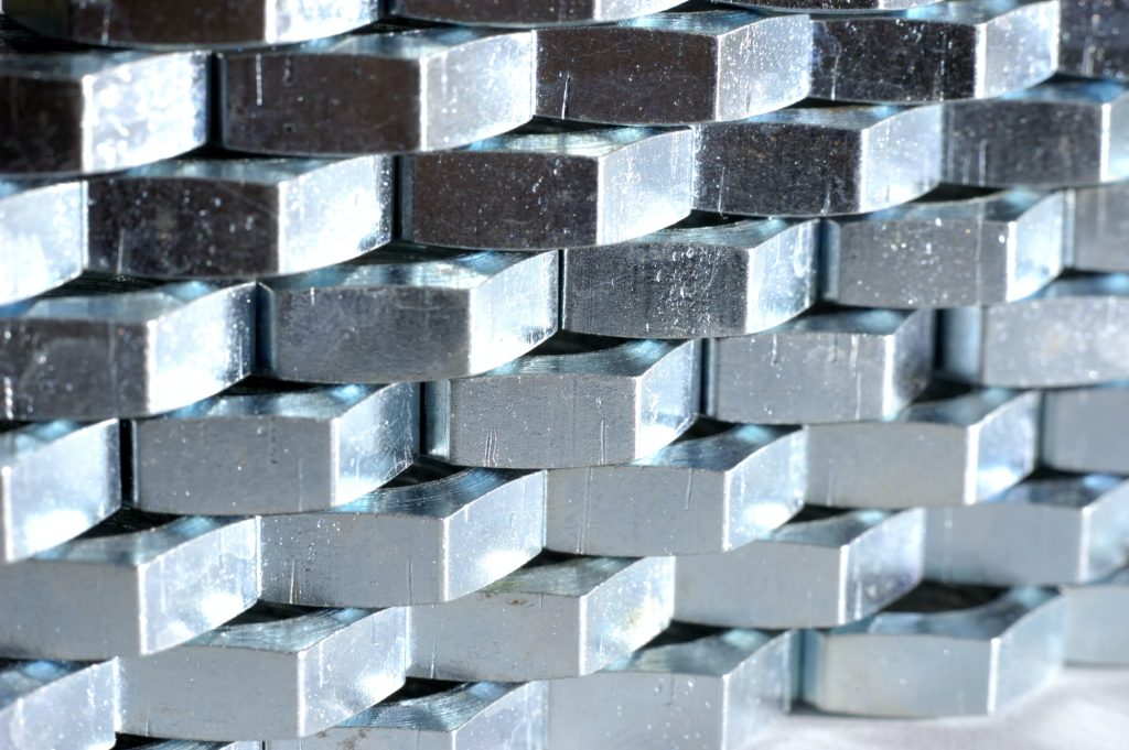 Close-up wall of numerous chrome metal nuts