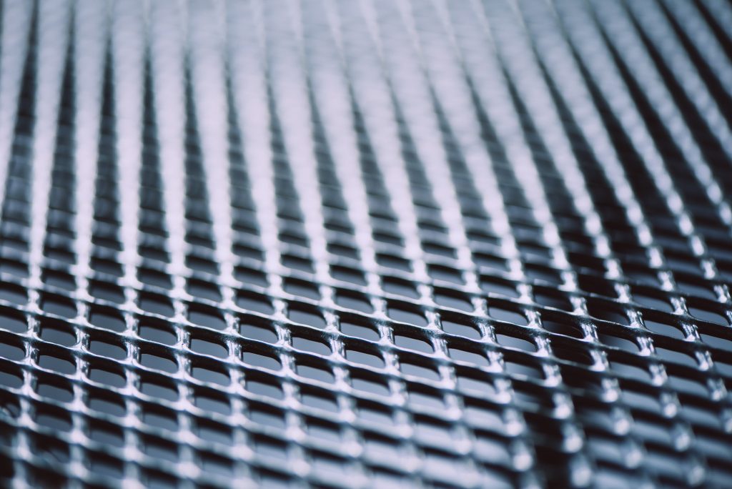 Metal background. Lattice texture with small cells grid. Selective focus point