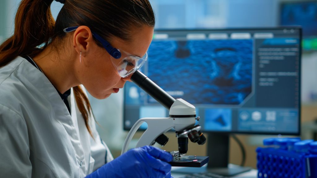 Portrait of scientist looking under microscope in medical lab